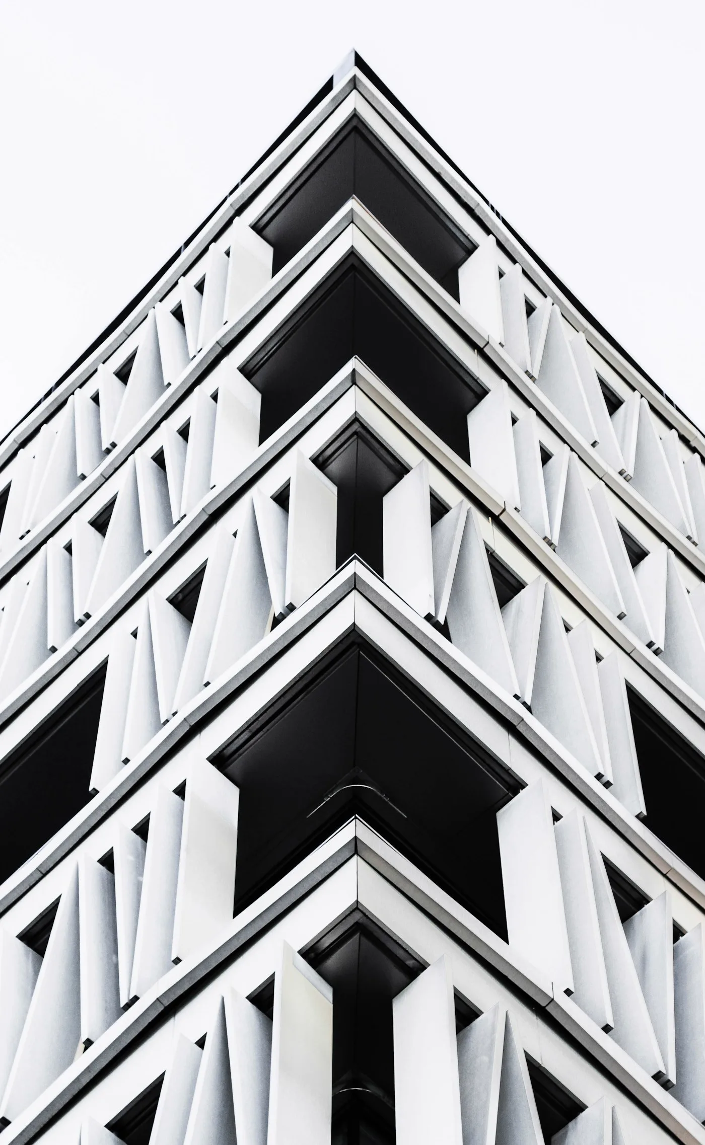 Black and white view looking up at a geometric high-rise building